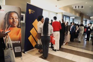 People line up for event registration by banners in a bright hallway.