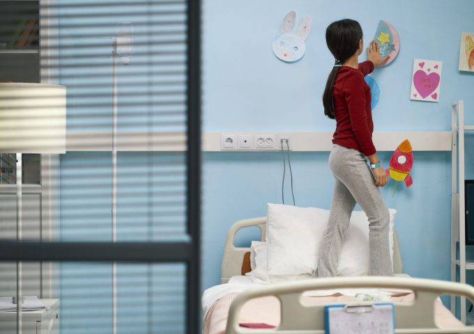 Little patient decorating ward with her drawings, she hanging them on the wall